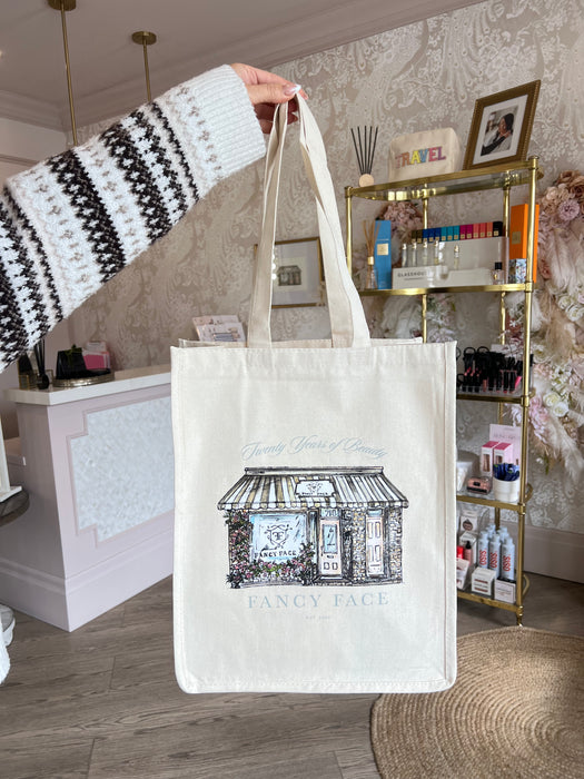 Person holding a tote bag with architectural design in a room with decor elements.